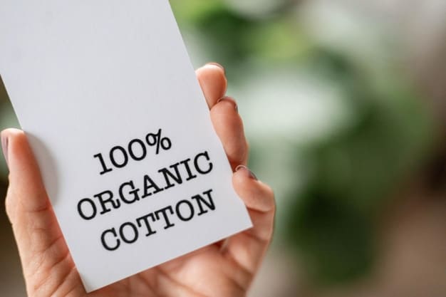 A close-up of a hand holding a tag on a garment, showing certifications like GOTS (Global Organic Textile Standard) or Fair Trade logos, indicating sustainable and ethical production.