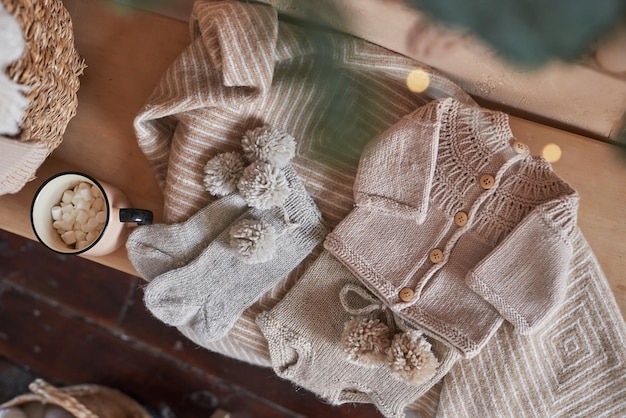 Detailed image of a collection of various knitwear pieces - sweaters, cardigans, and dresses in neutral and pastel colors, neatly arranged on a clothes rack.