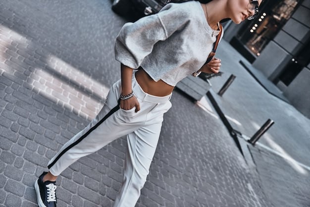Detailed image of a person wearing a stylish athleisure outfit - leggings, a crop top, a zip-up hoodie, and sneakers, posing in a modern, minimalist setting.