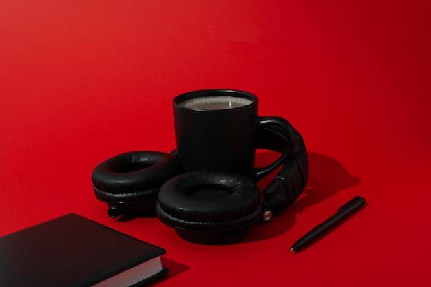 Close-up of a pair of noise-canceling headphones resting on a desk next to a laptop and a coffee mug, showcasing their sleek design and the ear cup material.