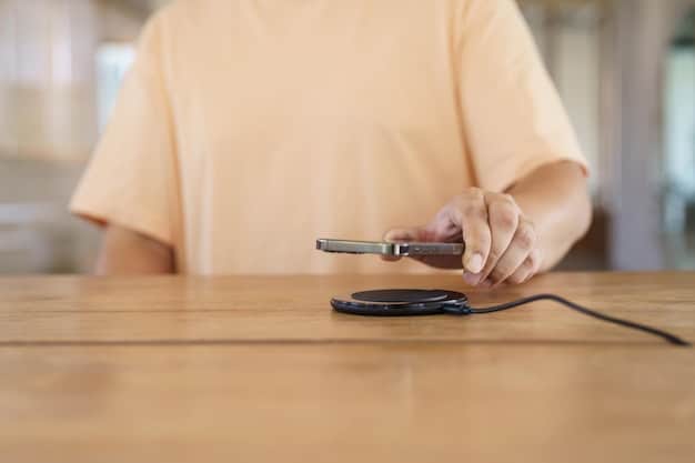 A person placing a smartphone on a wireless charging pad on their desk. The desk is clean and organized, with a laptop and other accessories in the background. The overall scene evokes a sense of productivity and efficiency.