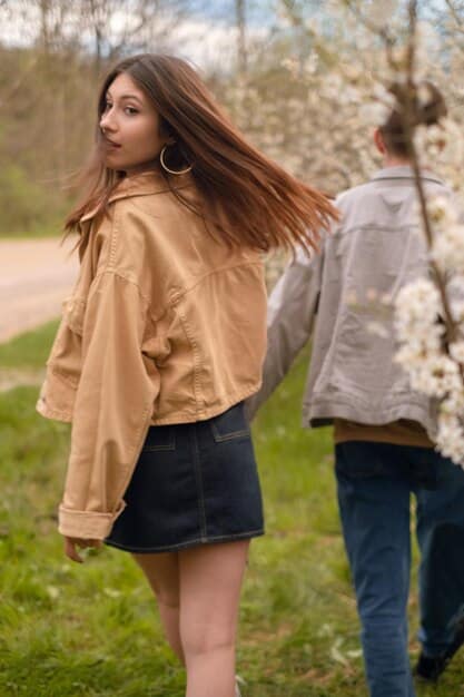 A split image showing two contrasting styles of spring outfits. On one side, a casual outfit featuring a denim jacket, t-shirt, and sneakers. On the other side, a more formal outfit with a floral dress, cardigan, and heels.