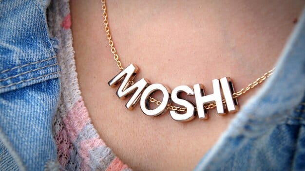 A close-up shot of a personalized necklace with a customized engraving, showcasing a couple's initials and a small heart charm. The necklace is displayed on a velvet cushion, emphasizing its elegance and sentimental value.
