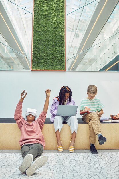 A group of students in a modern classroom, all wearing subtle VR headsets, actively engaging with a large, vibrant virtual projection of a human anatomy model floating in the center of the room. The scene should convey collaborative learning and advanced educational technology.