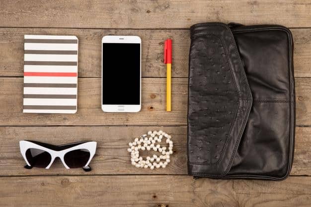 A flat lay showing a curated selection of Shein accessories, including a stylish mini-bag, a pair of oversized sunglasses, layered gold necklaces, and a stack of delicate rings, all arranged aesthetically on a light-colored surface.