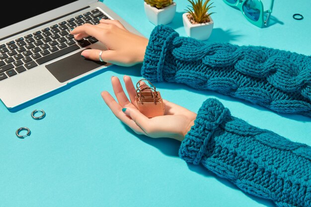 A close-up of a woman's hands typing on a laptop, showing a stylish yet subtle ring and a delicate bracelet, with a soft, cozy knit sweater in the background, subtly showcasing WFH accessories.