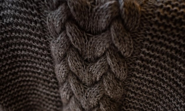 Close-up of a stylish knit sweater with intricate cable knit patterns and contrasting textures, possibly with a subtle flecked yarn visible, highlighting craftsmanship.