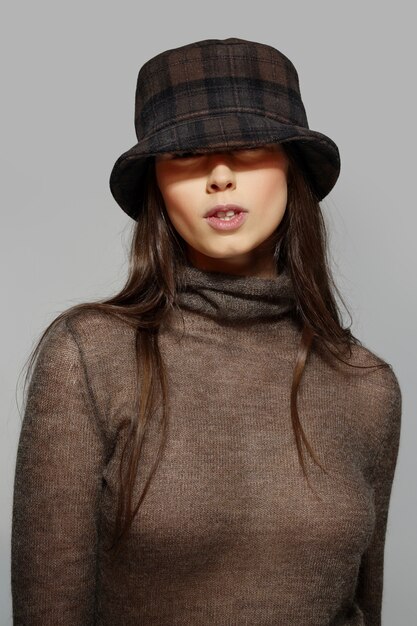 A stylish model wearing an oversized, soft knitted bucket hat, paired with a cozy sweater and delicate gold hoop earrings, showcasing a modern, comfortable fashion statement.