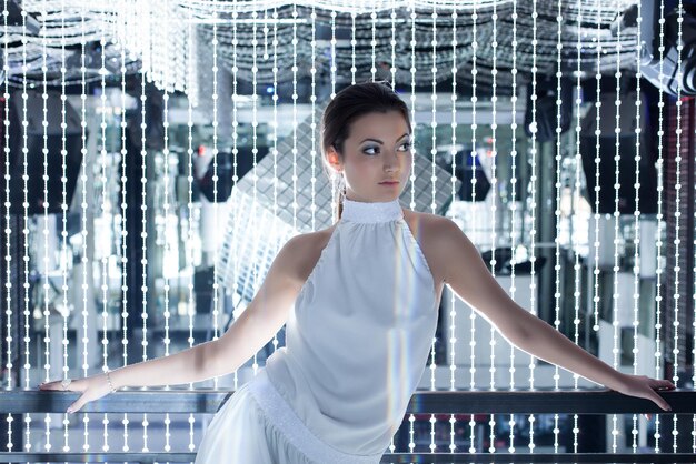 A mannequin showcasing a stunning, floor-length midnight blue satin gown from Shein's 2025 collection, featuring a cowl neck and a subtle side slit, illuminated by soft party lights.
