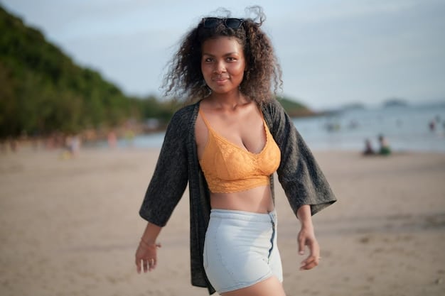 An athlete with an inverted triangle body type smiling confidently in a Shein swimsuit with a simple black top and a vibrant, patterned ruffled bottom at a sunny beach.
