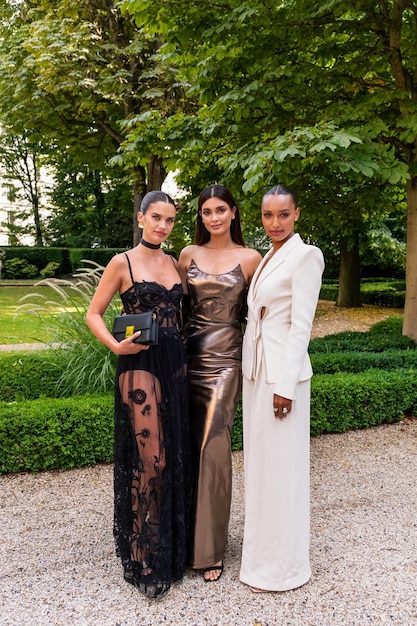 A diverse group of young women, each wearing a different elegant yet affordable dress from Shein's 2025 collection, smiling and posing together at a garden wedding venue.