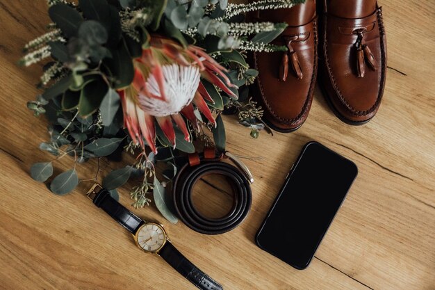 A flat lay showing a curated selection of vintage accessories, including a classic leather belt, a colorful silk scarf from the 70s, and a few ornate brooches, arranged alongside contemporary minimalist jewelry, on a textured background.