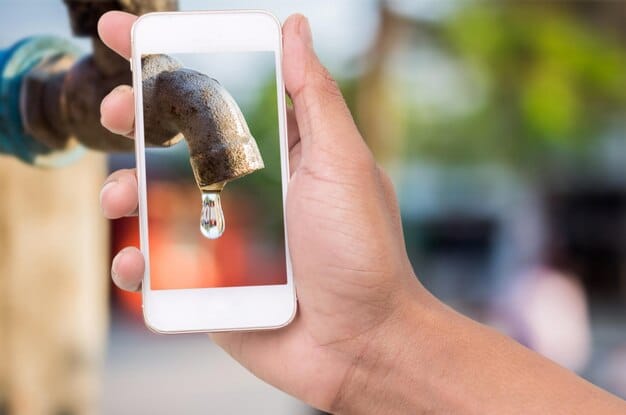 Close-up of a smartphone displaying a clear photo of a defective product, held by a person. The background features a simple home setting with organized shelves. Illustration of documenting evidence for returns.
