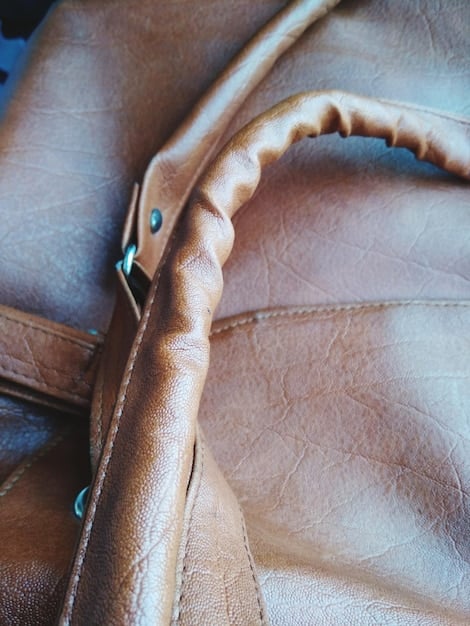 A detailed close-up shot of a high-quality leather handbag, showcasing the texture and stitching. The handbag is a classic design and color, suitable for various occasions. The image emphasizes the craftsmanship and materials, representing a valuable fashion investment.