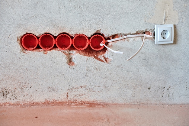 A close-up of a damaged electrical outlet with frayed wires, illustrating the importance of regular electrical inspections for home fire safety: prevention tips and emergency preparedness for 2025.