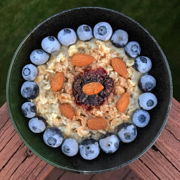 A close-up shot of a bowl of oatmeal topped with fresh blueberries, sliced almonds, and a drizzle of honey. The focus is on the texture of the oatmeal and the vibrant colors of the toppings, emphasizing a healthy and delicious breakfast option to Lower Your Cholesterol Naturally: 7 Foods to Add to Your Diet Starting Today.