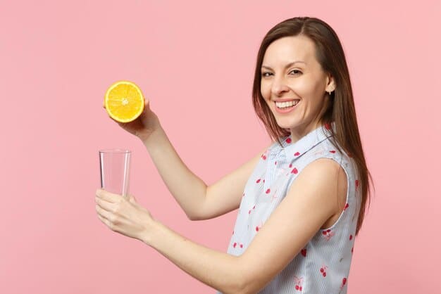 A woman smiling and holding a glass of water with lemon slices against a backdrop of fresh fruits and vegetables, symbolizing a healthy lifestyle and conscious food choices related to 'The Truth About Sugar: How to Cut Back and Improve Your Health in 2025.'